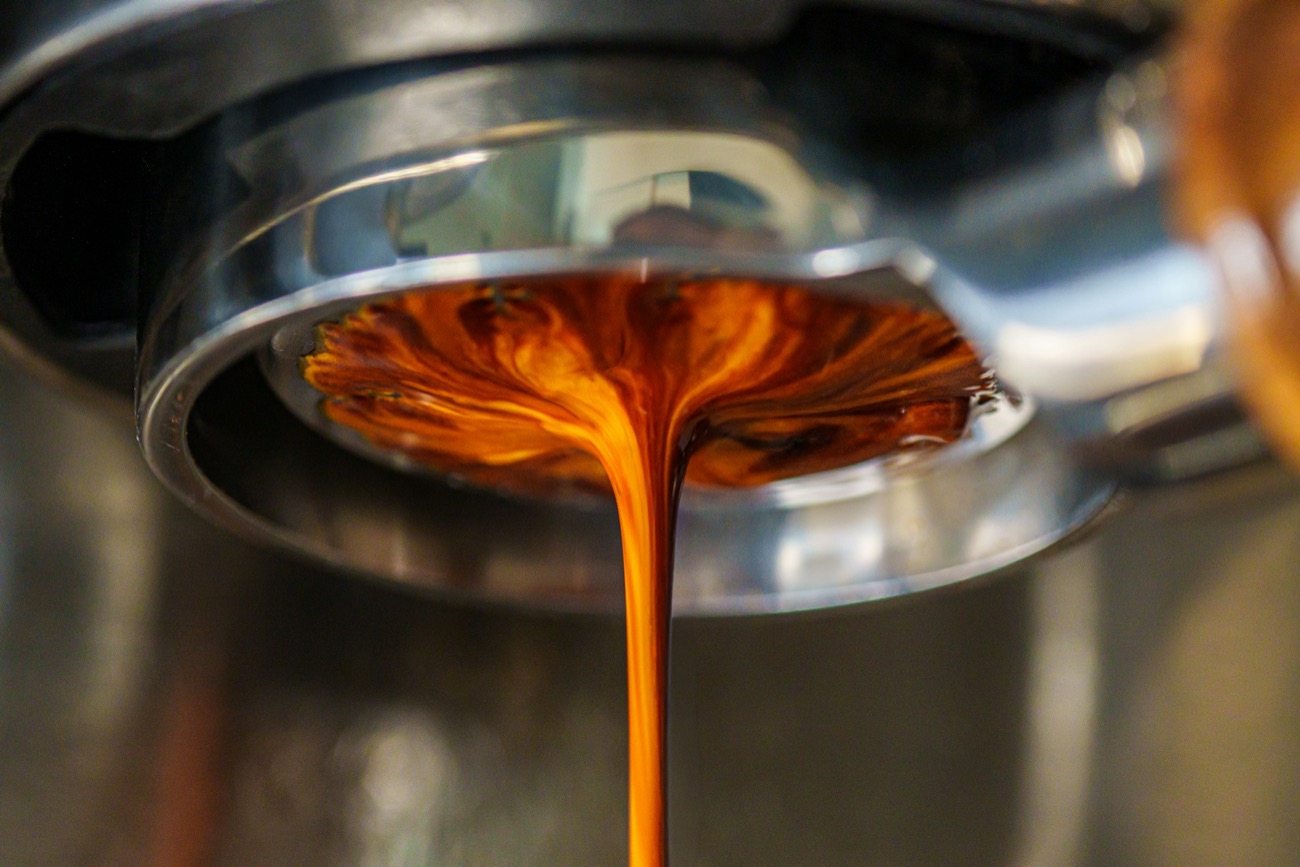 Espresso cayendo del portafiltro de una cafetera