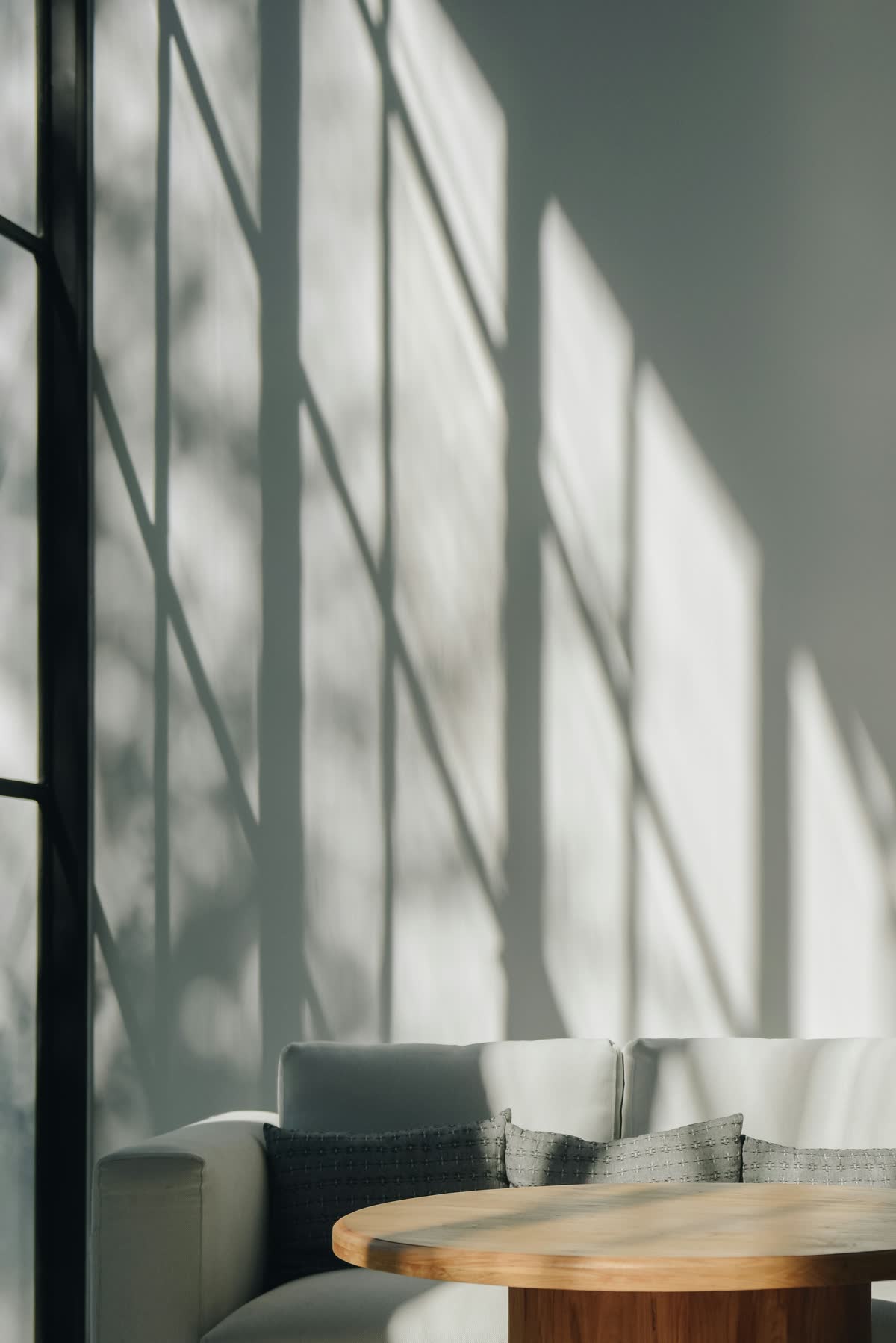 Luz de la tarde y sombras de una ventana sobre una pared blanca