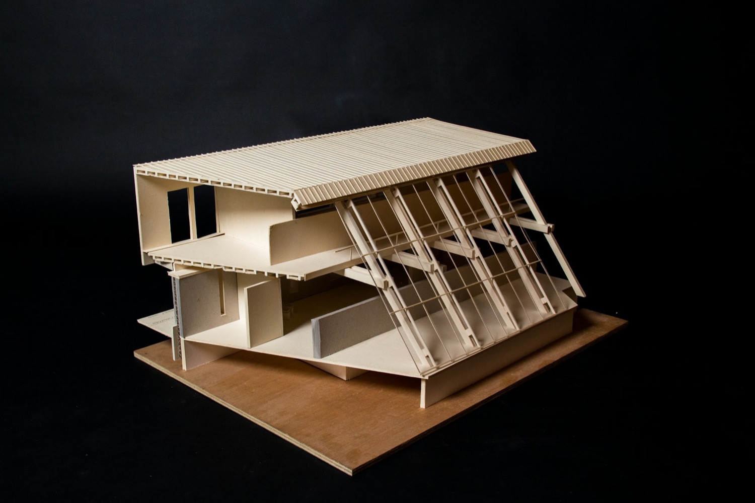 Maqueta de madera clara de una casa de tres niveles escalonados, sobre fondo negro